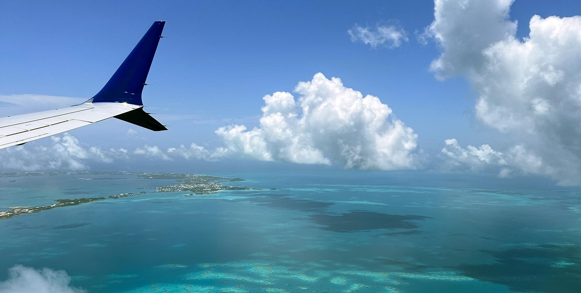 An aerial view showcases part of Bermuda's fishhook-shaped island chain, surrounded by vibrant turquoise waters and stunning coral reefs. The image highlights the natural beauty of this British overseas territory, known for its pink sand beaches and rich historical significance.