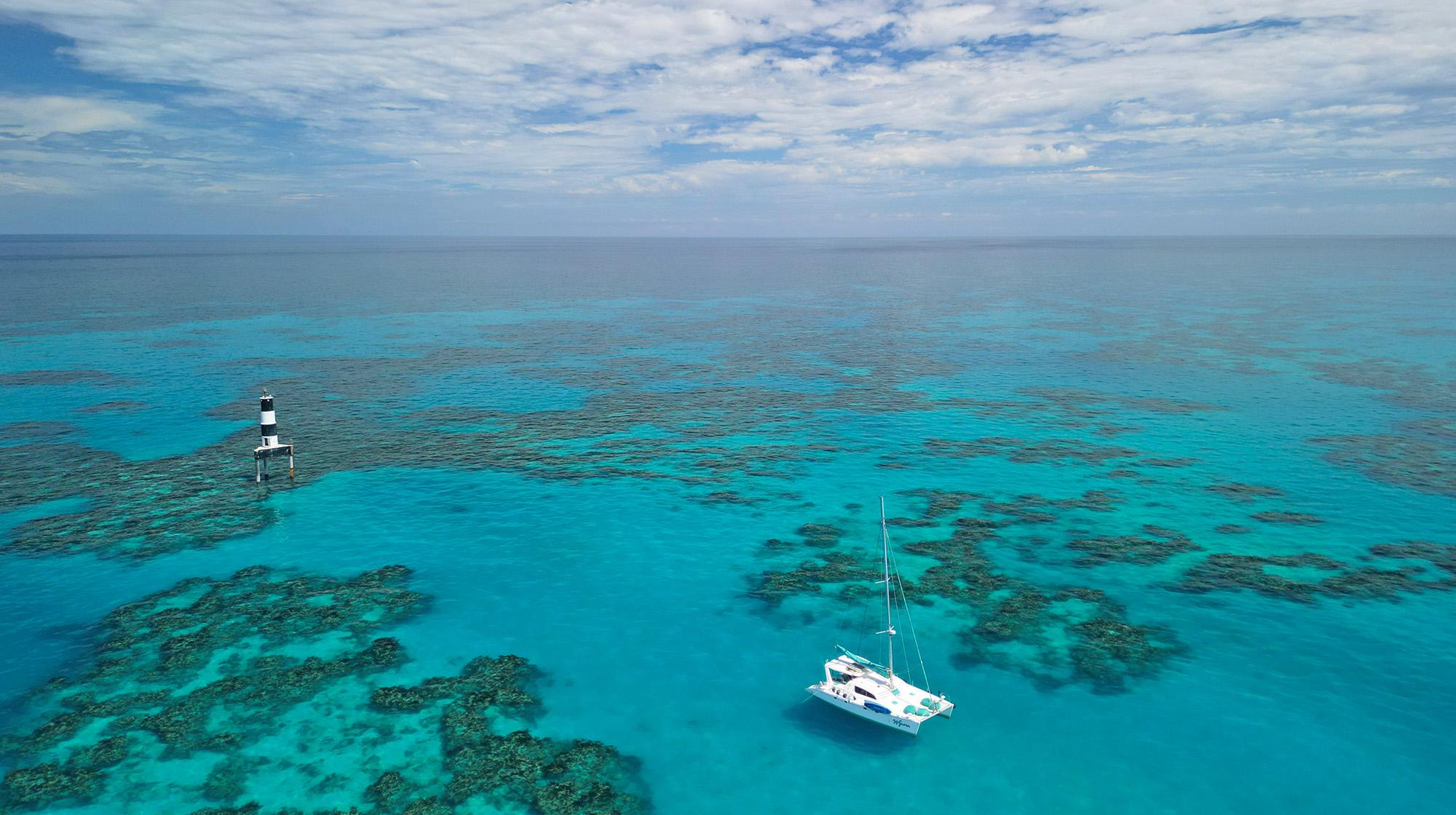A modern white catamaran sits anchored in the calm turquoise waters of the Atlantic Ocean, under a clear blue sky, evoking a sense of tranquility often associated with the mysterious Bermuda Triangle region. This picturesque scene contrasts with the infamous tales of ships and planes disappearing in the now familiar triangular area of the North Atlantic.